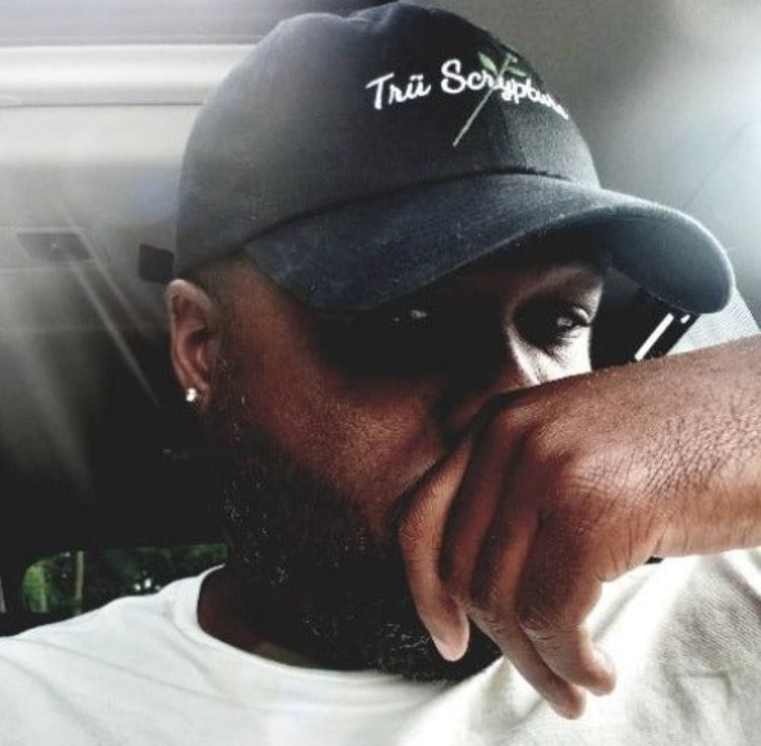 Picture of a model in  the Trü Scrypted Black Rose Dad Hat from the front view.